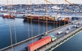 Rush hour traffic on a bridge above a container ship