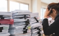 Office worker distressed with lots of paperwork on her desk.