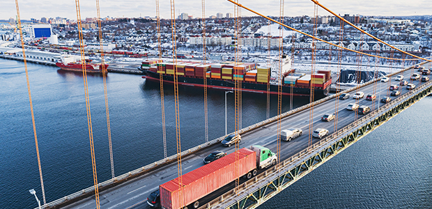 Rush hour traffic on a bridge above a container ship
