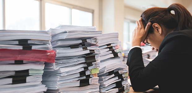 Office worker distressed with lots of paperwork on her desk.