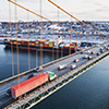 Rush hour traffic on a bridge above a container ship